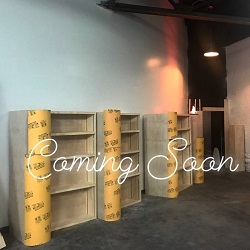An inside look at the new satellite location for Malaprop's. There are empty, unpainted shelves, and the words "Coming Soon" appear across the image.